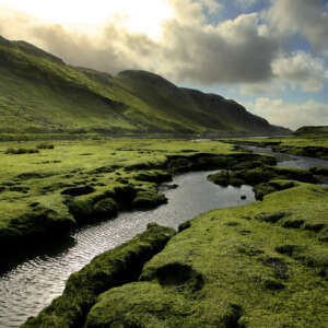 Green mountains with a stream flowing between them, in the Scottish highlands